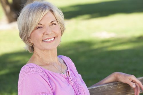 An attractive elegant and happy senior woman sitting outside and smiling