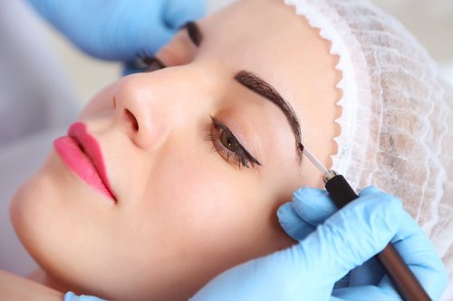 Cosmetologist applying microblading on eyebrows
